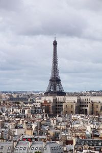 Tower in city against cloudy sky