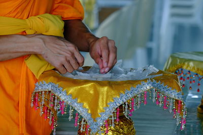 Midsection of monk with plastic bags in plate