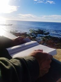 Low section of man sitting on book at beach