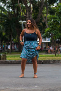 Portrait of young woman standing against tree