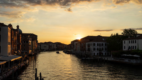 Canal amidst buildings against sky during sunset