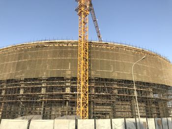 Low angle view of crane against clear blue sky