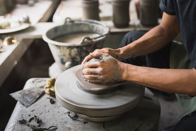 Midsection of craftsperson making pot at workshop