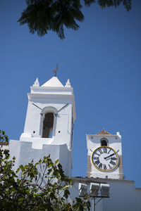 Low angle view of clock and bell tower of church against clear blue sky