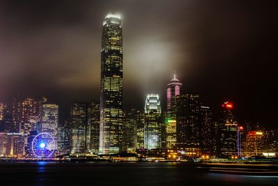 River in front of illuminated cityscape against sky at night