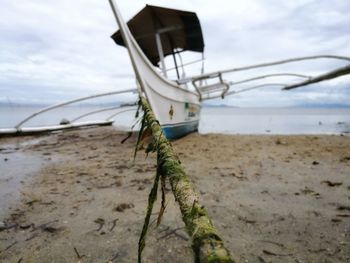 Close-up of boat moored on beach against sky