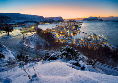 High angle view of townscape by sea against sky during sunset