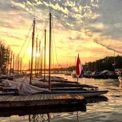 Boats moored at harbor against sky during sunset