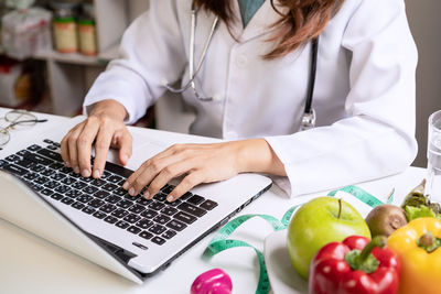 Midsection of woman using laptop on table