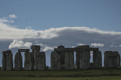 Built structure on landscape against cloudy sky