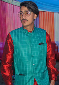 A indian young man with wearing kurta, pajama, nehru coat and sunglasses with looking sideways 