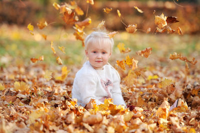 Portrait of cute girl sitting in park during autumn