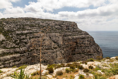 Scenic view of rocky mountain by sea against sky