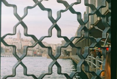 Close-up of metal fence against buildings in city