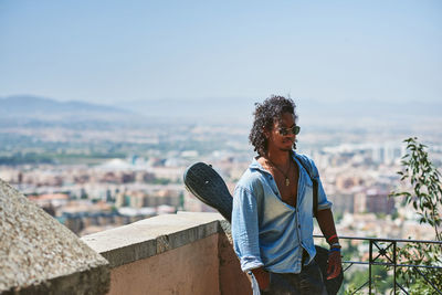 Man standing on railing against cityscape