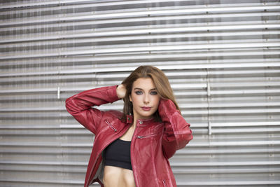 Portrait of beautiful young woman standing against corrugated iron shutter