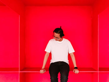 Full length of woman standing against red wall