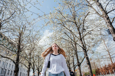 Young woman standing against bare tree