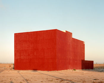 Red brick wall by sea against clear sky