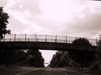 Bridge over road against cloudy sky