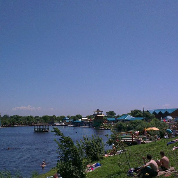 clear sky, water, copy space, blue, built structure, nautical vessel, tree, river, architecture, transportation, building exterior, nature, scenics, tranquility, lake, sea, tranquil scene, incidental people, large group of people