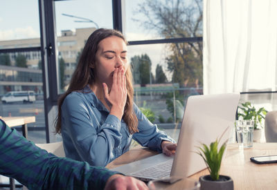 Portrait of young woman using laptop at office