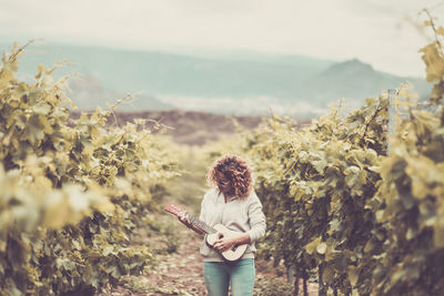 Mature woman playing guitar on field