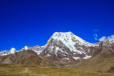 Scenic view of snowcapped mountains against clear blue sky