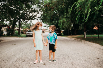 Two young kids holding hands and wearing homemade fabric masks