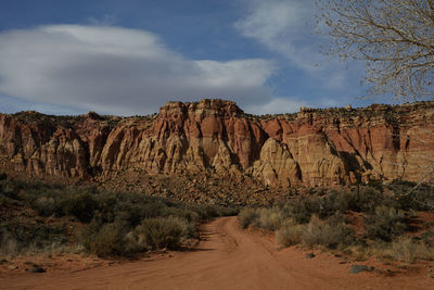 Rock formations by road against sky