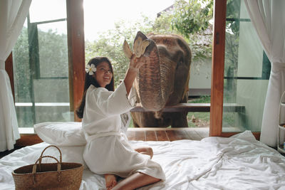 Portrait of smiling young woman relaxing on bed at home