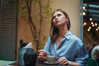 Young woman looking away while standing on table