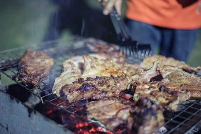 Midsection of man preparing meat on barbecue grill