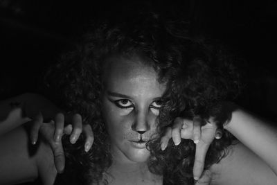 Close-up portrait of young woman with painted face in darkroom