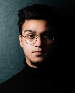 Portrait of young man in eyeglasses against wall