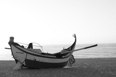 Boat moored on beach against clear sky