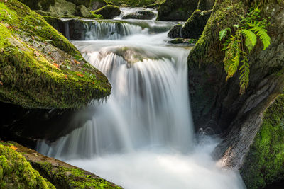 Long exposure of a waterfall flowing through the woods at watersmeet in exmoor 