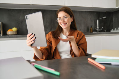 Midsection of woman using mobile phone while sitting on table