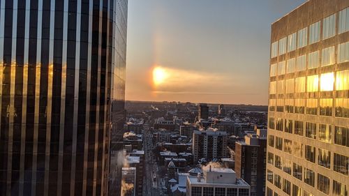 Modern buildings in city against sky during sunset