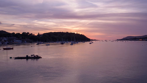 Sailboats in sea at sunset