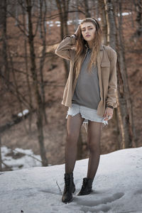 Full length of woman standing on snow covered tree