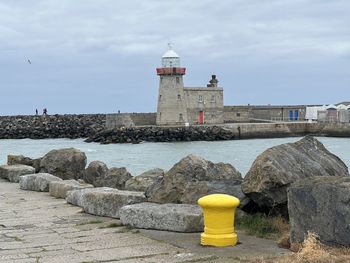 Lighthouse by sea against sky