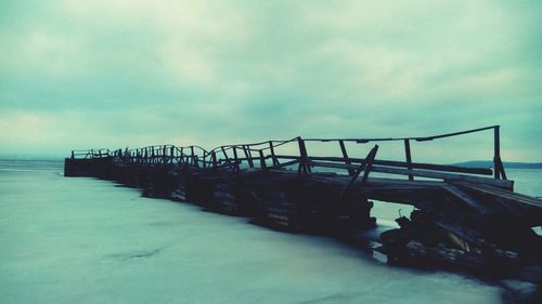 Pier on sea against cloudy sky