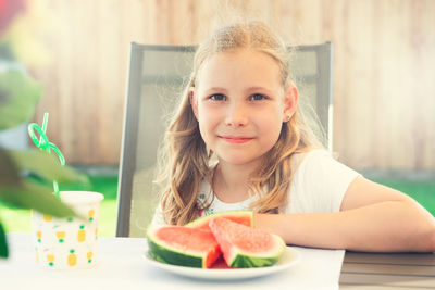 Portrait of cute girl with fruits on table in yard