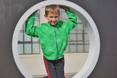 Cheerful boy playing on outdoor equipment at playground during summer