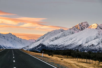 Road by mountains against sky during sunset