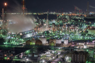 Aerial view of illuminated industry against sky at night