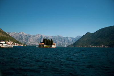 Scenic view of sea and mountains against clear blue sky