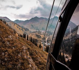 Overhead cable cars over mountains against cloudy sky