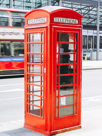 Red telephone booth on sidewalk in city